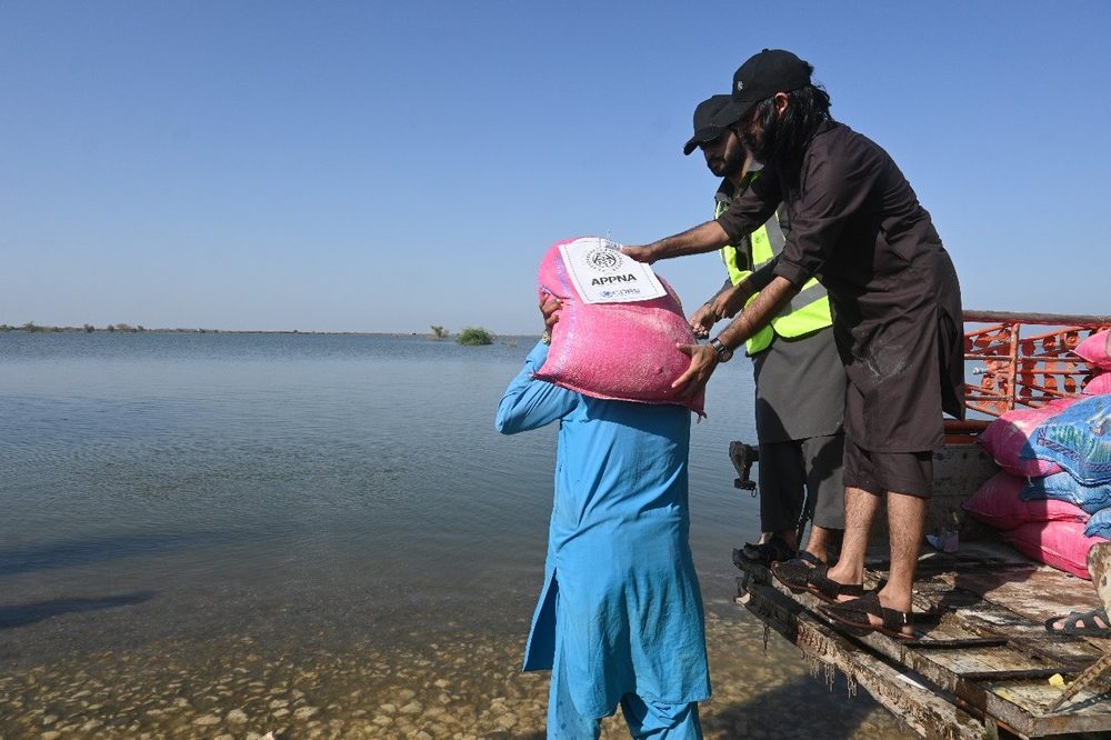 Relief supplies handed across floodwater from a boat