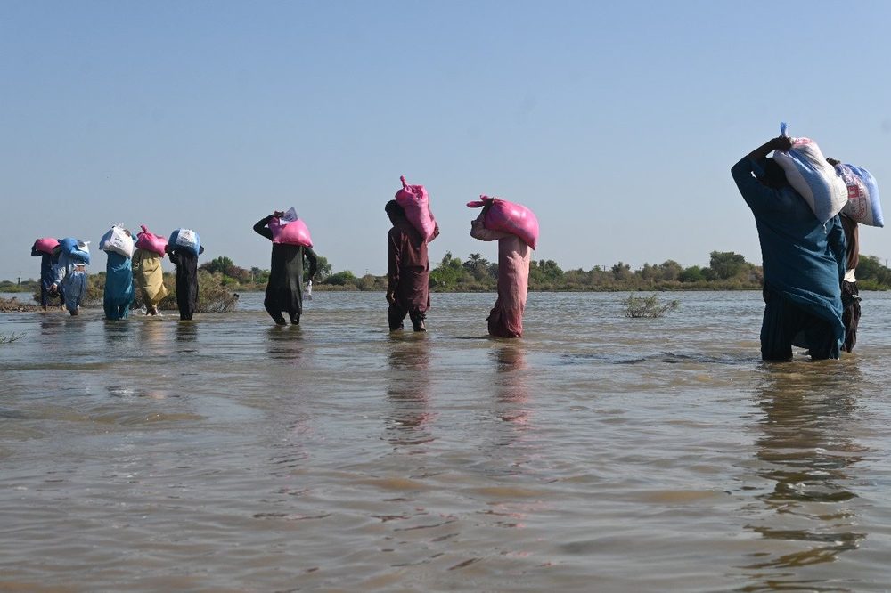 Families carrying CDRS ration packs through floodwater