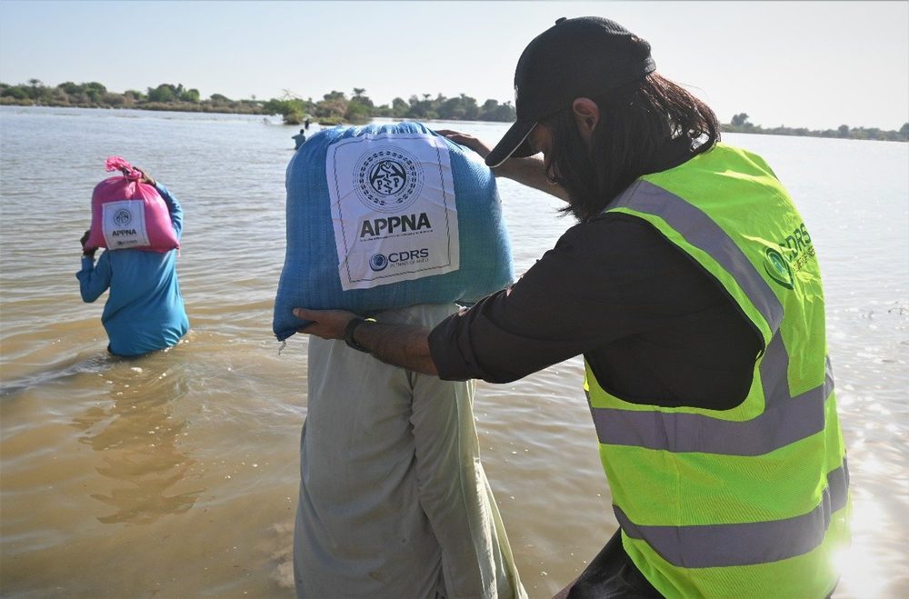 A CDRS team member carrying a ration pack through floodwater