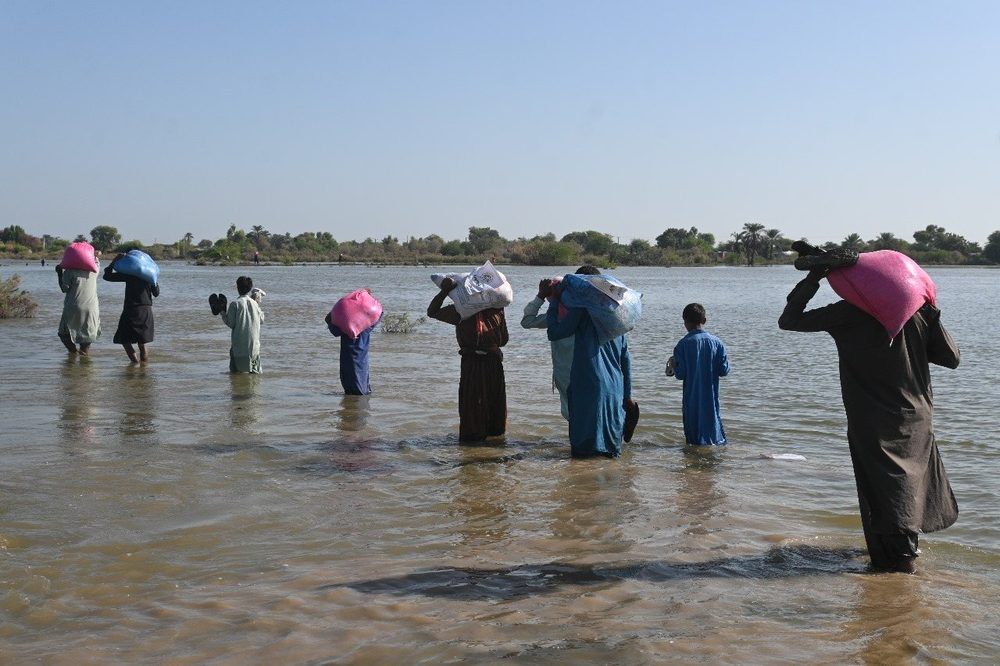 A family wading through floodwater to reach a CDRS distribution