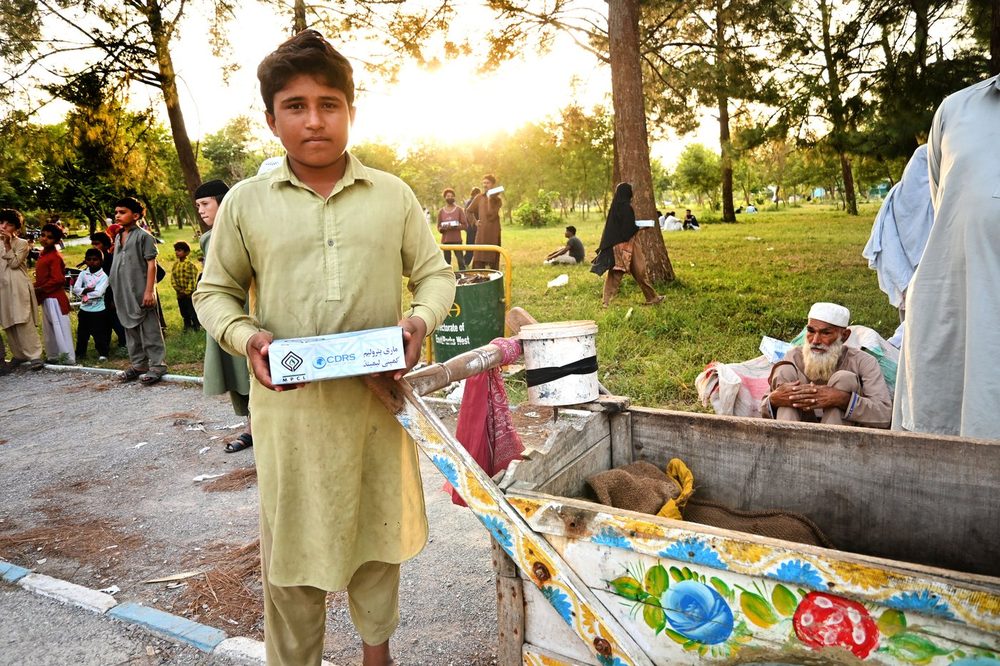 A boy with his meal beside a cart