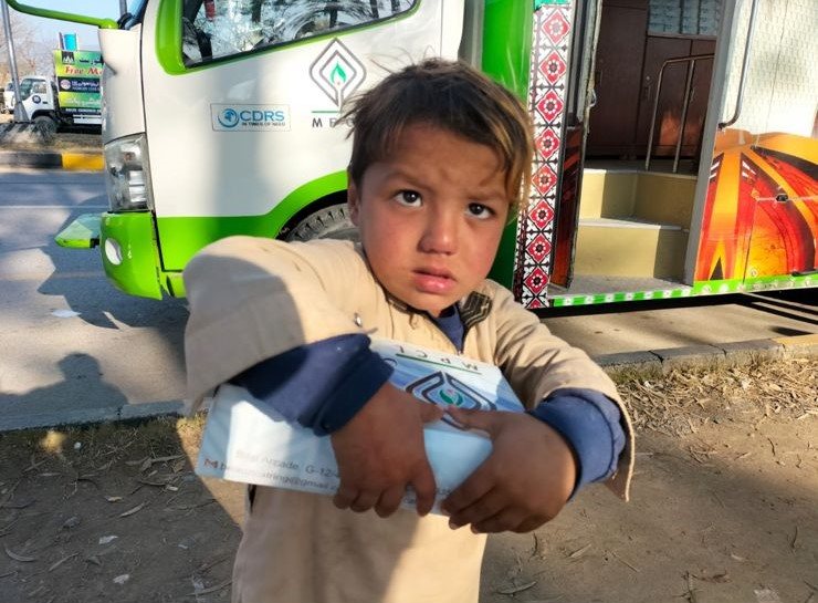 A child with a Mari Dastarkhwan meal at the van