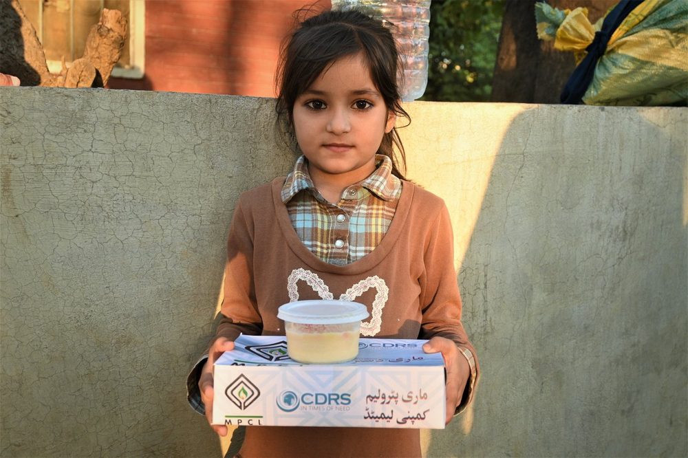 A girl holding a CDRS Mari Dastarkhwan meal box