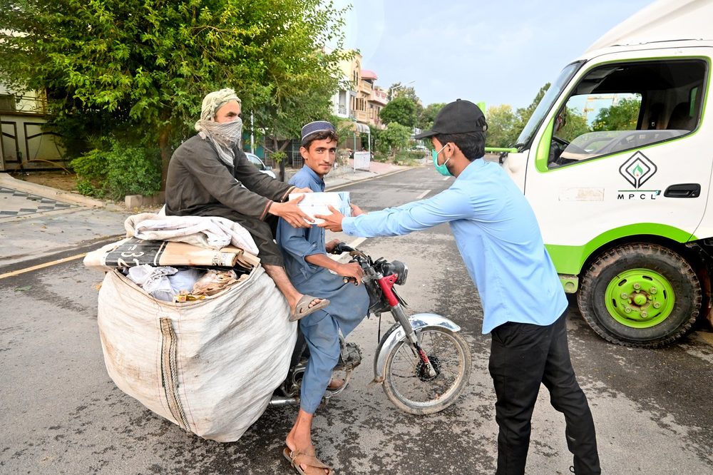 A meal handed to a family on a motorbike