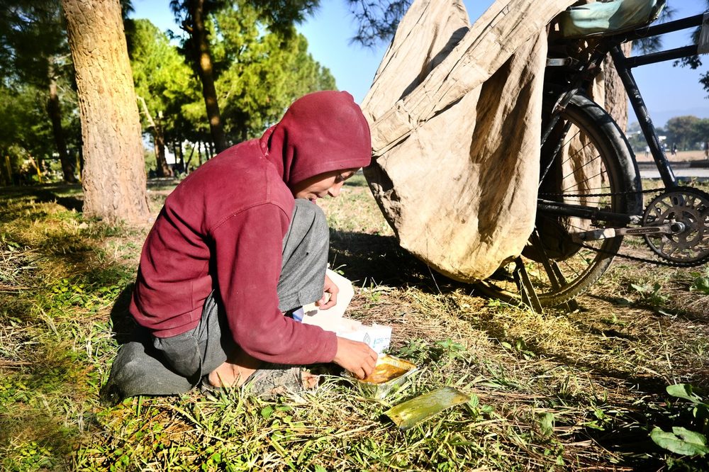 A woman eating a Mari Dastarkhwan meal at the roadside