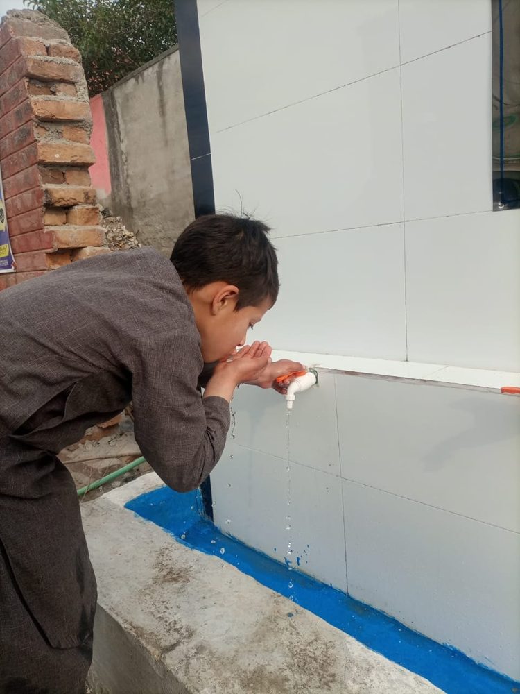 A boy drinking from a Wipe Out Thirst tap
