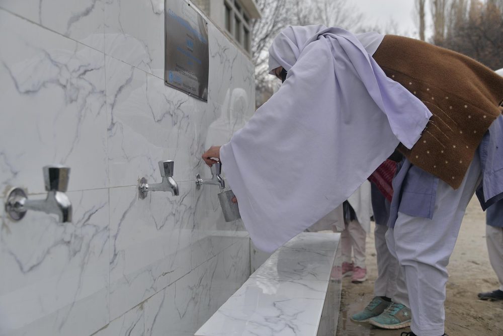 A pupil drinking at the Wipe Out Thirst water point